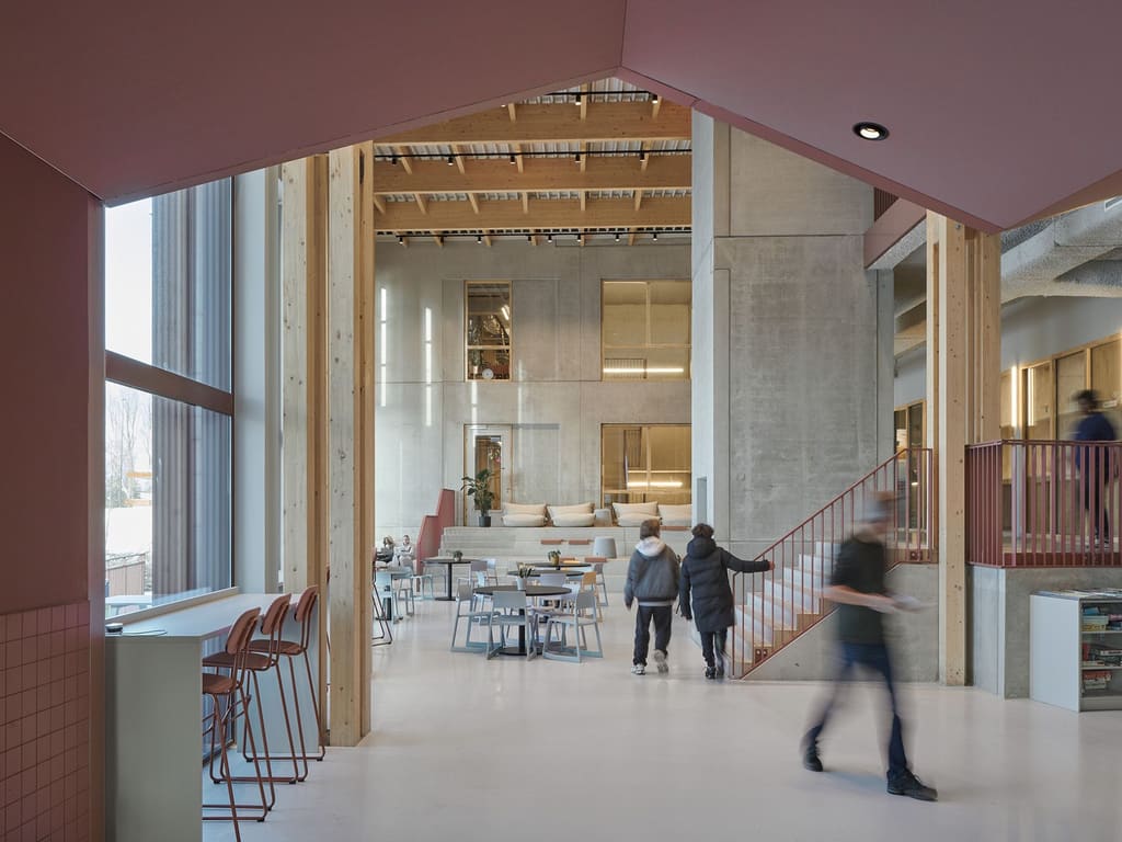 Het grand café van Xplore: een hoge ruimte met een houten constructie, trappen en leerlingen
